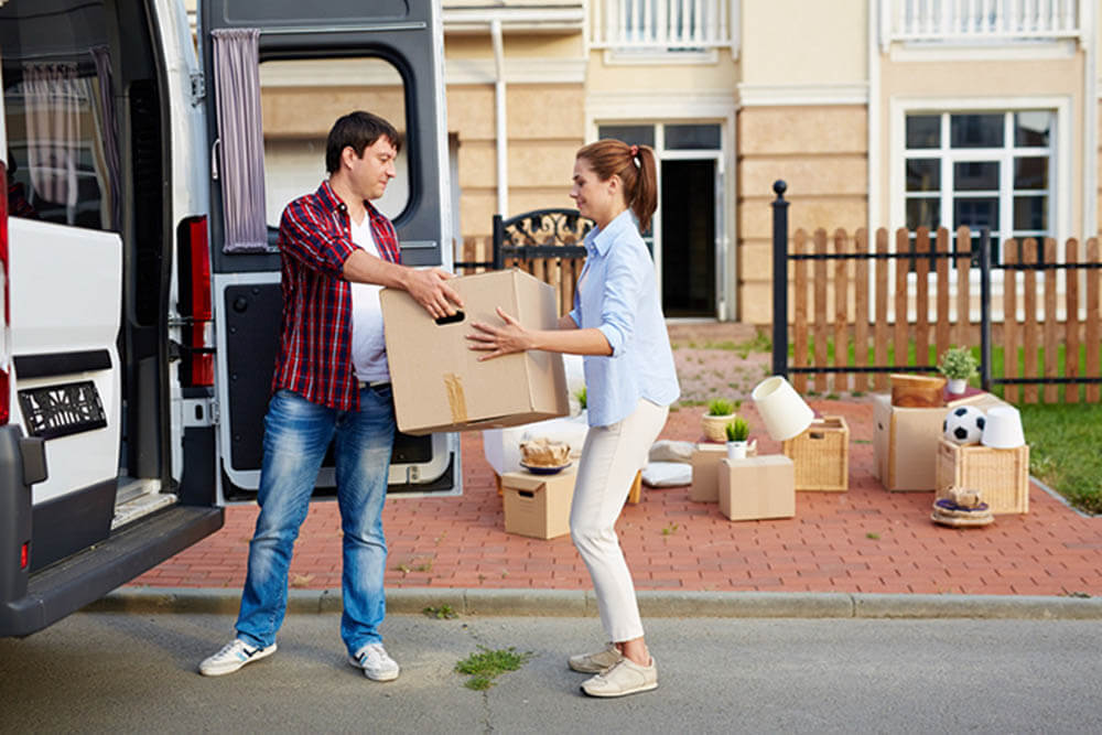 A man and woman moving a large box into a moving van